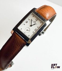 BAUME & MERCIER Modèle Hampton Montre bracelet d'homme en acier, cadran blanc, index appliqués et délicat chemin de fer. Secondes à 6 heures. Bracelet cuir marron et boucle deployante assortie. En l'état. Mécanisme non garanti.