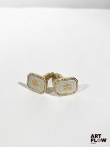 BURBERRY Paire de boutons de manchette en métal doré et argenté à décor guilloché centré du logo de la marque 1,5 x 1 cm env.