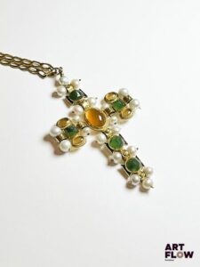 Croix en or jaune 750‰, portant des poinçons italiens et français, de style étrusque, composée au centre d’une belle citrine cabochon sur une frise enrubannée, la croix représentée par un ensemble de perles blanches, petites citrines cabochons et probablement des néphrites de forme carrée facettées, soulignées par de l’émail noir. La croix suspendue sur une chaine en or jaune 750‰ massive, maille cheval avec chainette de sécurité. Poids : 32.29 g brut Dimensions croix : 8 x 4.5 cm – Longueur chaine : 59 cm Expertise : Philippine Vanheems
