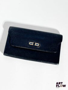 DELVAUX Porte feuille en cuir grainé noir, bijouterie en métal doré, fermeture par bouton pression. Dimensions : H. 11 x L. 18 cm