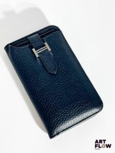 HERMÈS Coque de téléphone / iPhone en cuir noir, bijouterie en métal argenté, fermeture à rabat. Dimensions : H. 15 x L. 8 cm