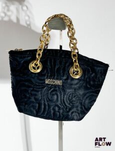 MOSCHINO Petit sac en tissu matelassé à décor de fleurs, bijouterie et chaine en métal doré, fermeture éclair. Dimensions : H. 13 x L. 22 cm