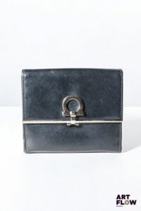 SALVATORE FERRAGAMO Porte feuille et monnaie en cuir noir, bijouterie en métal argenté, fermoir à pression et à rabat. Dimensions : 10 x 12 cm Bon état général (quelques marques d'usage)