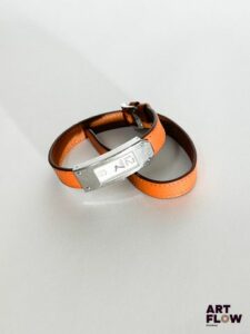 HERMÈS Modèle Kelly II Référence : KT1.210 Montre bracelet de dame à boitier en acier vissé, signé et numéroté, cadran à fond blanc à deux index chiffres arabes appliqués, montée sur un bracelet double tour en cuir orange à boucle ardillon signée Hermès. Mouvement quartz. Diamètre boitier : 15 x 41 mm Longueur : 36 cm environ Bracelet rapporté Avec facture