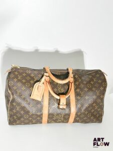 C.C... x LOUIS VUITTON Sac Keepall 50 en toile enduite monogrammée et cuir naturel Customisé par l'artiste C.C... (présente des inscriptions ton sur ton) Dimensions : 50 x 30 x 23 cm En l'état, usures (patine d'usage, craquelure, frottements)