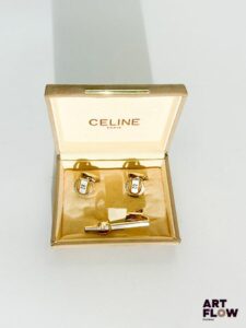 CELINE Paire de boutons de manchette et pince à cravate, l'ensemble présente un fer à cheval et le monogramme doré sur fond argenté. Dimensions de la pince à cravate : 5 cm Dimension des boutons de manchette : 1,5 cm Bon état général Dans sa boîte
