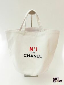 CHANEL Sac seau en toile de coton blanc avec inscription à l'avant "N°1 de CHANEL" et au dos une rose rouge Dimensions : 43 x 30 x 26 cm Très bon état général malgré le "C" qui décolore