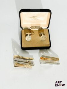 Ensemble comprenant : – YVES SAINT LAURENT, 4 pinces à cravate, deux argentées et deux dorées, l'ensemble est monogrammé "YSL". – BALMAIN, 2 pinces à cravate, l'une dorée monogrammée "PB" et l'autre argentée avec inscription "Pierre Balmain" – GIVENCHY, paire de boutons de manchette avec logo, dans sa boite Bon état général