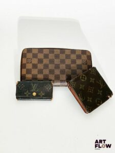 LOUIS VUITTON Lot comprenant : – un étui pour quatre clés habillé de toile monogramme épurée, fermeture bouton-pression, dimensions 10 x 5,5 x 1 cm – un portefeuille en toile toile monogrammée, dimensions 10 x 10 cm – un porte-monnaie damier, dimensions 21 x 12 cm En l'état