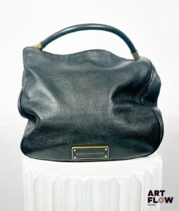 MARC JACOBS Sac à main en cuir noir se fermant à l'aide d'un bouton aimanté, avec une bandoulière détachable, 3 poches intérieures Dimensions : 30 x 40 x 10,5 cm Très bon état général, usures à la bijouterie
