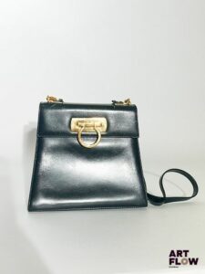 SALVATORE FERRAGAMO Sac à main ou à épaule en cuir synthétique lisse noir Bijouterie dorée Dimensions : 20 x 18 x 9 cm Traces de griffure sur le cuir, anse découpée, bijouterie présentant des éclats