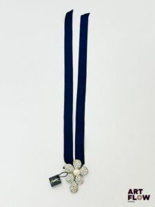 YVES SAINT LAURENT Collier ruban marine orné d'un pendentif en métal argenté formant fleurs pavée de strass et centré d'une perle fantaisie Signé Dimensions du pendentif : 5,5 x 4 cm Quelques strass manquants