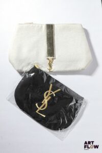 YVES SAINT LAURENT Ensemble de deux pochettes en tissu beige et noir, l'un brodé du monogramme, bijouterie en métal doré Dimensions : 17 x 28 cm pour le plus grand