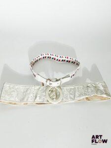 YVES SAINT LAURENT Lot de 2 ceintures comprenant : - Une ceinture blanche élastique tressée, avec des détails rouges et bleus, une boucle en résine transparente. Dimensions (sans la boucle) : environ 75 × 3 cm. - Une ceinture blanche avec une broderie argentée représentant des fleurs, une boucle blanche et un charm argenté. Dimensions (sans la boucle) : environ 86 × 8 cm. Usures.