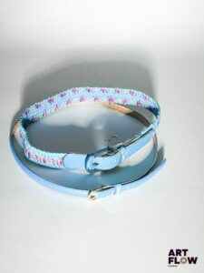 YVES SAINT LAURENT Lot de 2 ceintures comprenant : - Une ceinture bleu clair avec une bijouterie dorée. Dimensions (sans la boucle) : 90 × 1 cm. - Une ceinture élastique tressée bleue avec des détails dans les tons violets, et une boucle bleue transparente. Dimensions (sans la boucle) : 75 × 3 cm.