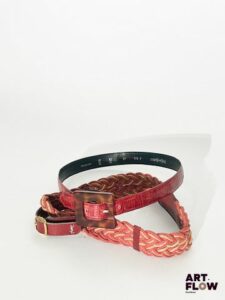 YVES SAINT LAURENT Lot de 2 ceintures comprenant : - Une ceinture en cuir rouge imitation crocodile. Dimensions (sans la boucle) : 78 × 2,3 cm. Marques d'usure. - Une ceinture tressée de couleur rouge et beige, avec une bijouterie dorée. Dimensions (sans la boucle) : 74 × 5 cm. Marques d'usure.