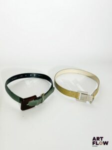 YVES SAINT LAURENT Lot de 2 ceintures comprenant : - Une ceinture vert foncé avec une boucle en résine marron foncé, possédant un charm doré en forme d’anneau. Dimensions (sans la boucle) : 78 × 2,5 cm. - Une ceinture vert kaki avec une bijouterie argentée. Dimensions (sans la boucle) : 71 × 2,5 cm. fermoir cassé