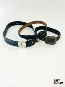 YVES SAINT LAURENT Lot de 3 ceintures comprenant : - Une ceinture bleu marine avec un charm rond doré et l'inscription « Yves Saint Laurent ». Dimensions (sans la boucle) : 78 x 2,7 cm. Marques d'usure. - Une ceinture bleu marine avec une bijouterie argentée. Dimensions (sans la boucle) : 100 x 4 cm environ . Infimes traces. - Une ceinture grise avec des charms en forme de cœur doré et l'inscription « YSL ». Dimensions (sans la boucle) : 87 x 3 cm. Marques d'usure et manque au niveau de la bijouterie.