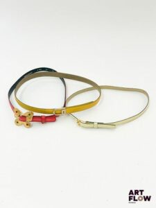 YVES SAINT LAURENT Lot de 3 ceintures comprenant : Une ceinture jaune, avec une bijouterie dorée. Dimensions (sans la boucle) : 79 × 2 cm. Marques d'usure. Une ceinture blanc cassé, avec une bijouterie dorée. Dimensions (sans la boucle) : 74 × 1,5 cm. Petites taches rouges. Une ceinture rouge avec une bijouterie dorée, dont la boucle en forme de papillon est ornée de quatre strass. Dimensions (sans la boucle) : 76 × 1,5 cm. Marques d'usure.