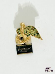 YVES SAINT LAURENT Un clip d'oreille en métal doré formant un oiseau pavé de strass dans les tons verts 3,5 x 4 cm L'autre clip manquant